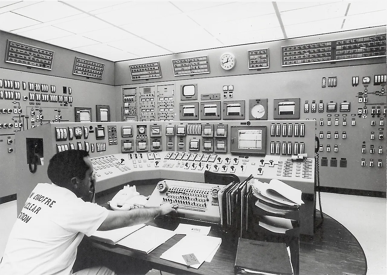 Black and white photograph of the San Onofre Nuclear Generating Station control room in 1968, showing operators at a large curved instrument panel with overhead lighting