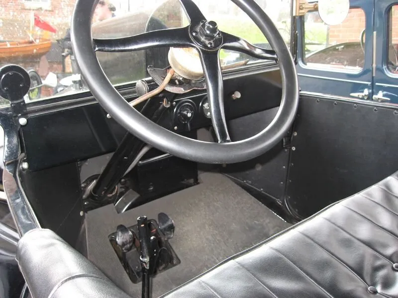 The interior of a 1920 Ford Model T, showing the steering wheel and floor pedals.