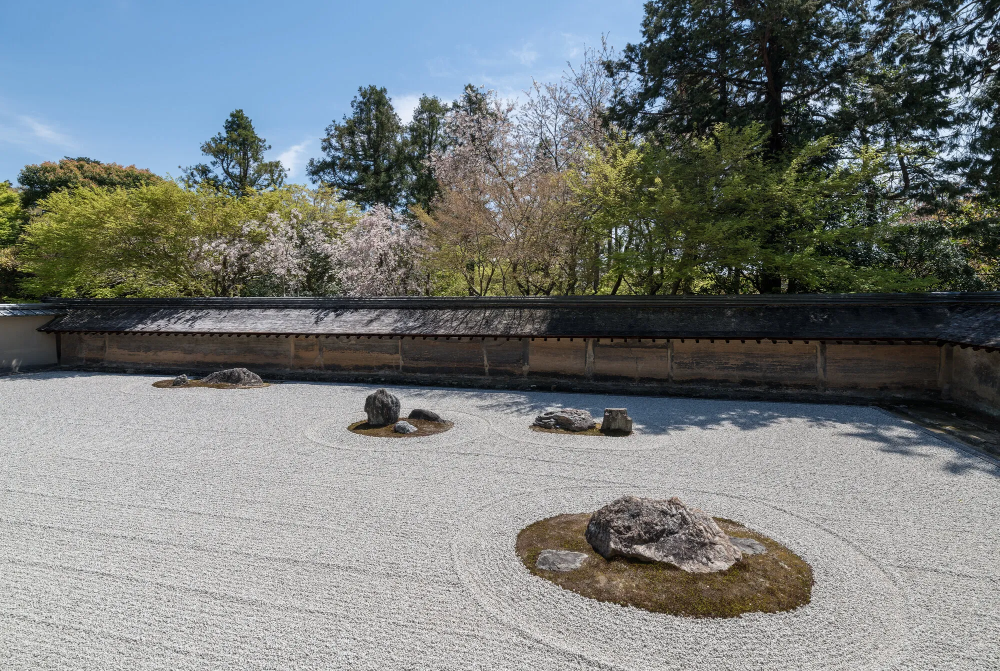 The dry landscape stone garden at Ryoan-ji, Kyoto, with raked gravel around fifteen arranged stones